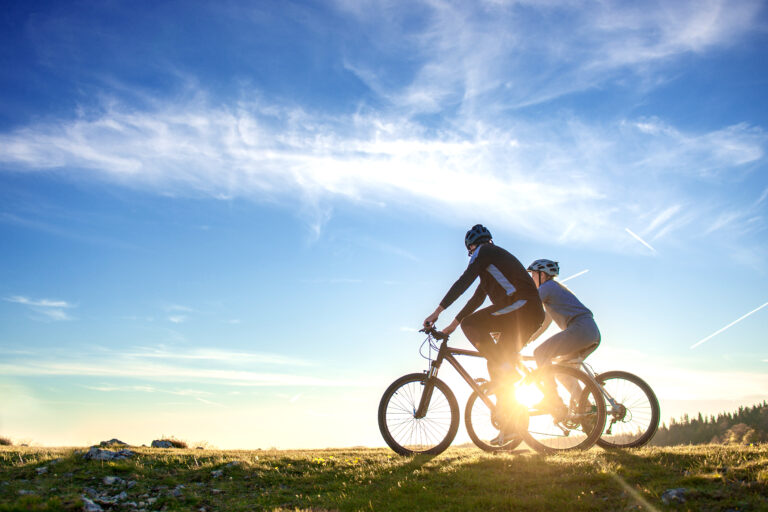 Happy mountain bike couple outdoors have fun together on a summer afternoon sunset.